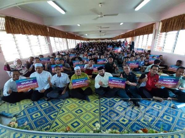 Che Rashid (depan, tiga kanan) bersama guru dan pelajarnya memegang plakad World #QuranHour selepas selesai membaca al-Quran beramai-ramai di SMK Sura semalam.