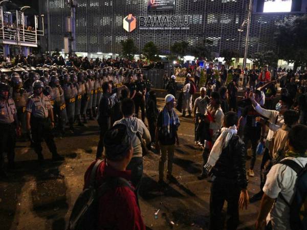 Polis Indonesia berdepan penunjuk perasaan ketika demonstrasi di luar pejabat Badan Pengawas Pemilu (Bawaslu) di Jakarta malam semalam. - FOTO AFP