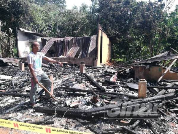 Anak sulung Zaharah, Azmi Mohamad, 53, menunjukkan tempat api bermula yang memusnah rumah ibunya.