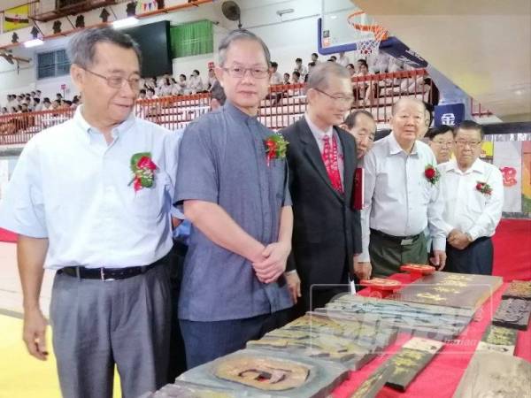 Boon Chye (dua, kiri) melihat seni ukir kayu tulisan Cina sempena Pameran Pendidikan Kebudayaan di Sekolah Menengah Poi Lam (SUWA) hari ini.