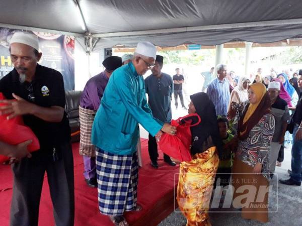 Mahfuz (dua, kiri) menyampaikan sumbangan kepada asnaf yang terpilih di Masjid Al Kauthar, Titi Besi, Alor Setar petang tadi.