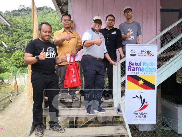 Mohd Rosli (tengah) ketika penyerahan sumbangan Bakul Kasih Ramadan kepada Yusuf (dua dari kiri) di Long Busang, Belaga, Sarawak baru-baru ini.