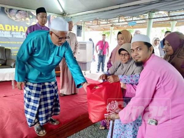 Mahfuz (kiri) menyerahkan sumbangan kepada 250 penerima sumbangan sempena Iftar Ramadan 2019 di Masjid Al-Kauthar, Titi Besi, Alor Setar semalam.