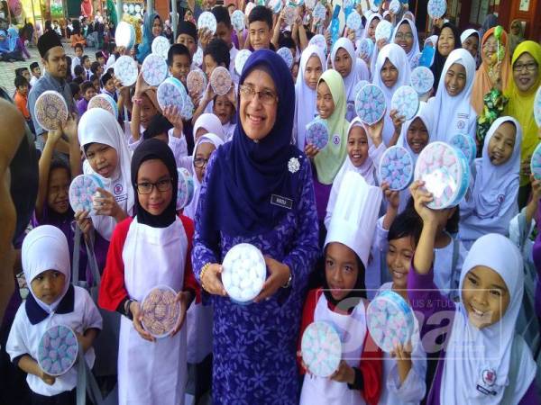 Norzila (tengah) dan Hannah dan Hayrah (sebelah) bersama-sama murid yang menerima sumbangan biskut raya pada majlis itu di Bukit Baru, hari ini.