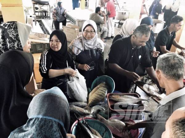 Fuziah (tengah) dan Rashima menimbang ikan yang ingin dibeli pengunjung sewaktu berlangsungnya program itu, di Pantai Sepat hari ini.