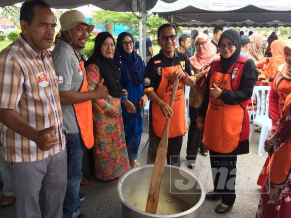 Zainol Fadzi (dua dari kanan) meluangkan masa menumis ramuan bubur lambuk pada program berkenaan.