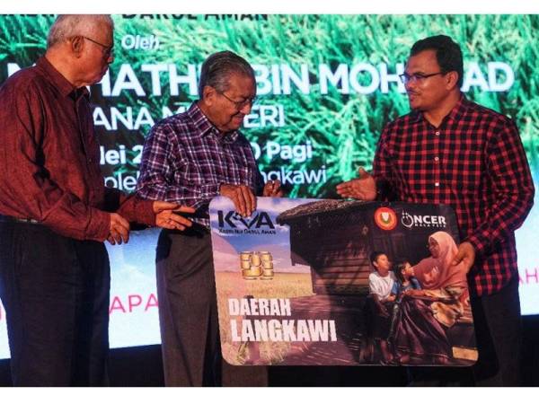 Dr Mahathir (tengah) menyerahkan replika kad KIDA kepada Muhammad Arof (kanan) pada Majlis Pelancaran KIDA di Kompleks Angkatan Pertahanan Awam (APM) Langkawi, di sini hari ini.