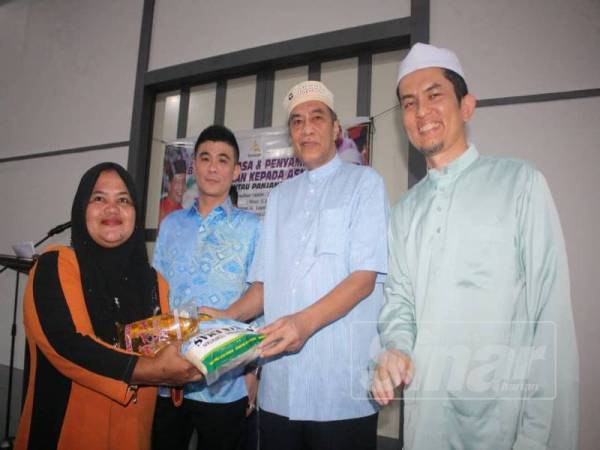 Husam (dua, kanan) menyerahkan sumbangan pada Majlis Berbuka Puasa dan Sumbangan kepada Asnaf Rantau Panjang di Kilang LLY Loyalty Logistics Sdn Bhd, Rantau Panjang.