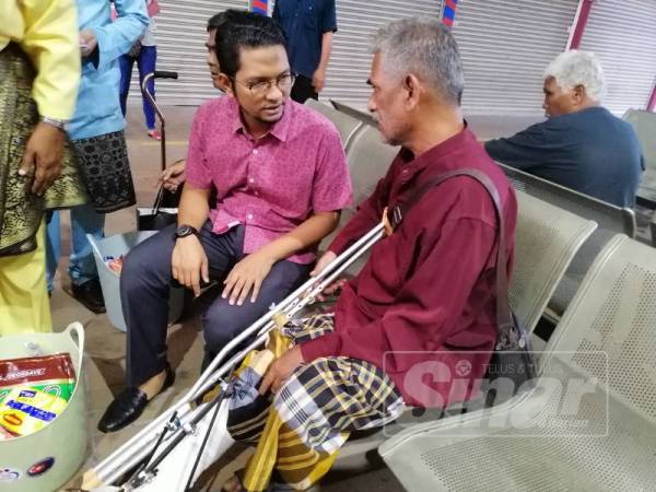 Sheikh Omar (kiri) menyerahkan sumbangan kepada salah seorang penerima di Terminal Bas dan Teksi Kluang.
