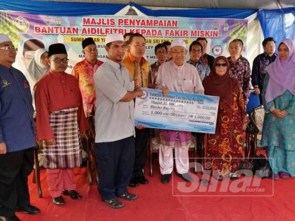 Harussani (empat dari kanan) menyempurnakan penyampaian cek replika sumbangan RM1,000 daripada Yayasan Muhibbah Fng Ah Seng kepada wakil Masjid Al-Halimi, Bandar Baharu sambil diiringi Ah Sng (empat dari kiri).