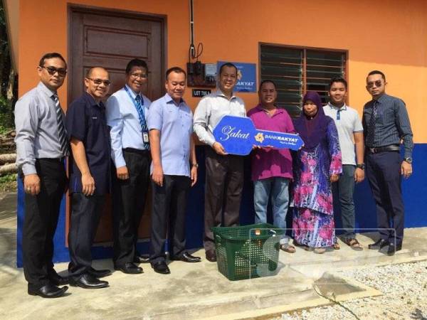 Hasnah dan Mohd Azman (kanan) menerima kunci rumah disampaikan Mohamed Al Namiri (tengah).