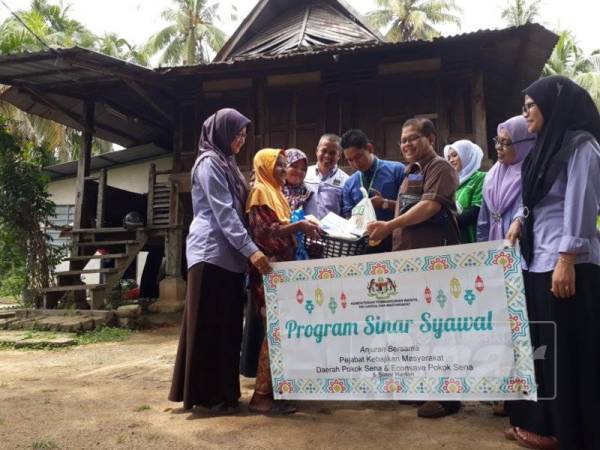 Ismail (empat kanan) bersama rombongan JKM dan Econsave menyerahkan sumbangan Sinar Syawal kepada Che Mah di rumahnya di Kampung Tanjung Musang, Pokok Sena.