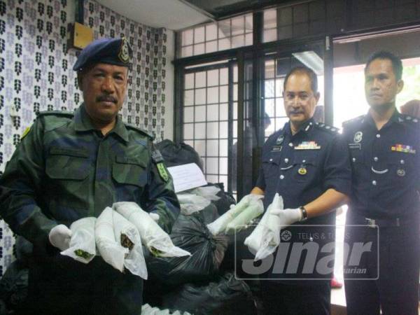 Abdullah (dua, kanan) dan Ramly (kiri) menunjukkan daun ketum yang berjaya dirampas.