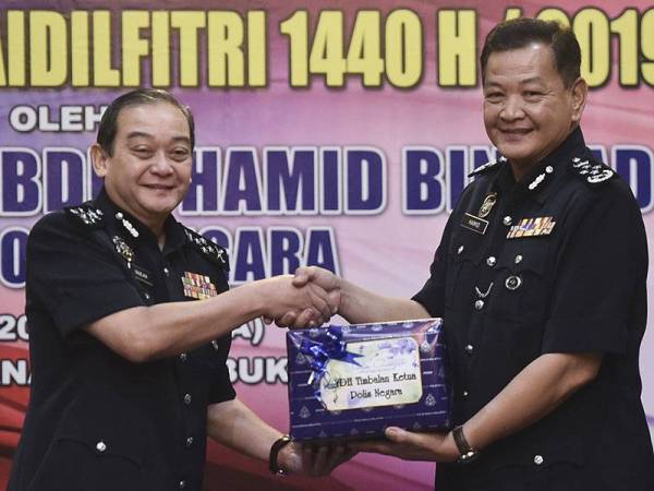 Ketua Polis Negara Datuk Seri Abdul Hamid Bador (kanan) menyerahkan bungkusan kuih raya kepada timbalannya Datuk Mazlan Mansor pada Majlis Penyerahan Bungkusan Kuih Raya Polis Diraja Malaysia sempena Hari Raya Aidilfitri di Ibu Pejabat Polis Bukit Aman hari ini. - Foto Bernama