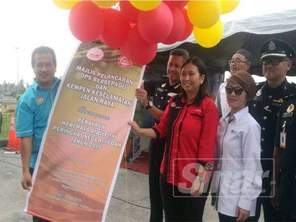 Azman (kiri) memegang banting Majlis Pelancaran Ops Bersepadu dan Kempen Keselamatan Jalan Raya bersempena Perayaan Hari Raya Aidilfitri Peringkat Kedah 2019 di Plaza Tol Hutan Kampung, semalam.