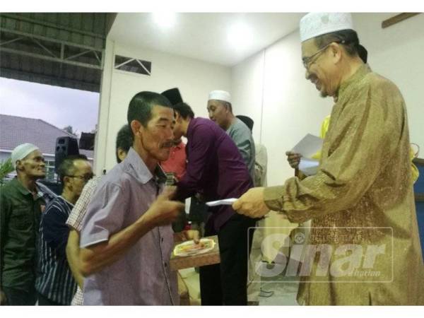 Ir Phahrolrazi (kanan) menyerahlan sumbangan wang tunai kepada salah seorang asnaf pada Majlis Iftar Pertubuhan Peladang, Majlis Pengurusan Komuniti Kampung (MPKK) dan Kawasan Rukun Tetangga (KRT) Dewan Undangan Negeri ( DUN) Alor Mengkudu di Dewan D'Awangan, di sini, semalam.