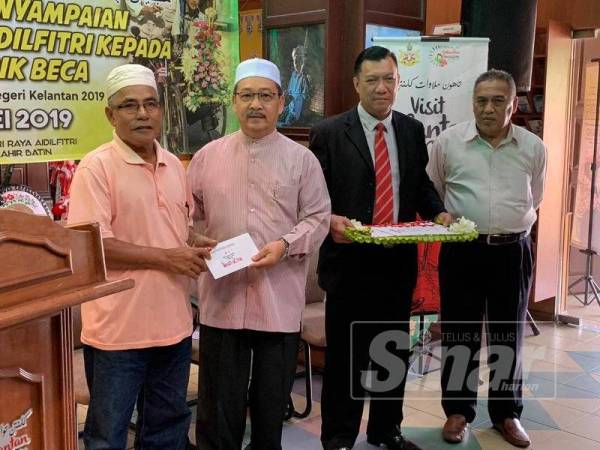 Anizam (dua dari kiri) menyampaikan bantuan kepada salah seorang penerima di majlis tersebut.