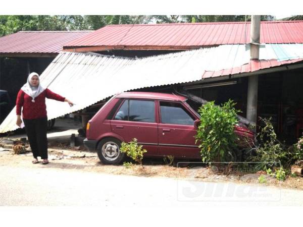 Saliza menunjukkan keadaan kereta terbabit yang rosak selepas merempuh garaj di rumahnya, semalam.