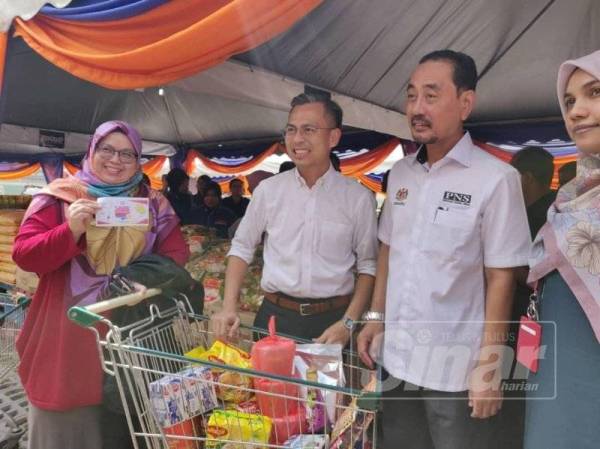 Fahmi (dua dari kiri) bersama pengunjung yang mengambil peluang happy hour mendapatkan keperluan makanan dengan harga rendah di Karnival Jimat Belanja PNSCare.