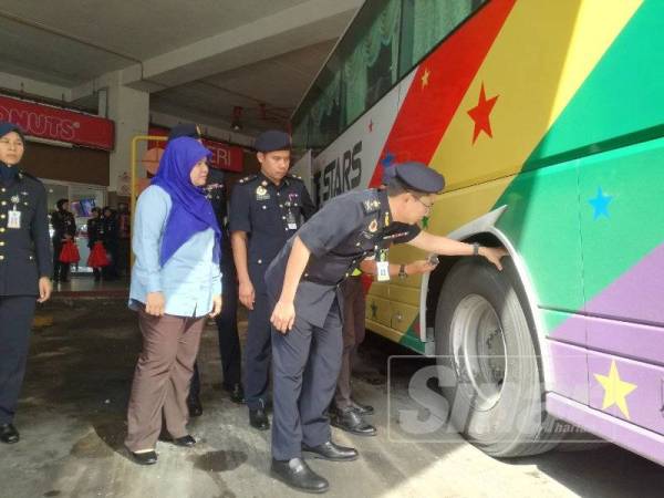 Azrin (kanan) memeriksa tayar sebuah bas ekspres pada pelancaran Op Raya di Terminal One, Seremban semalam.