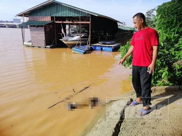 Penduduk Kampung Pasir Pekan, Mohd Nasir Abdul Kadir, 53, menunjukkan mayat warganegara Thailand yang ditemui terapung ditarik dengan bot ke jeti Pasir Pekan.
