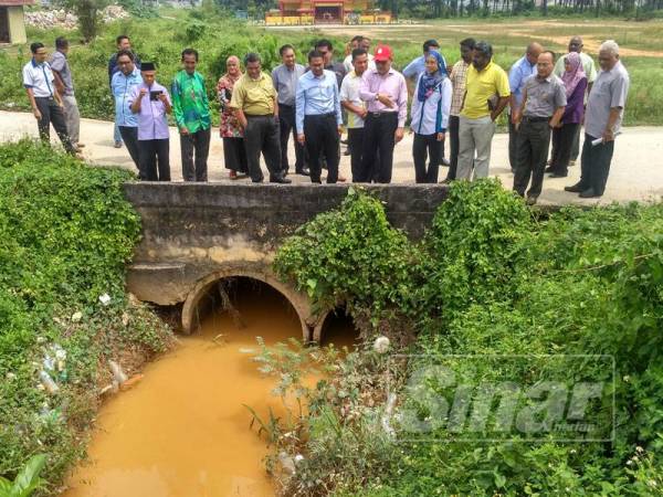 Izham dan beberapa pihak berkaitan meninjau salah satu kawasan saliran yang dilihat menjadi punca kepada masalah banjir di kawasan Meru.