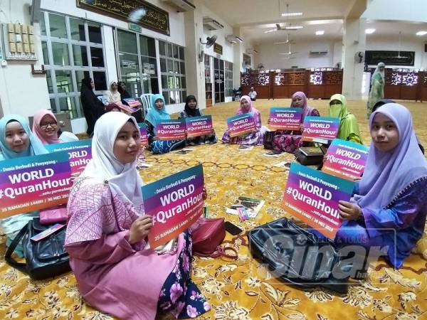 Peserta memegang poster World #QuranHour sebelum majlis membaca al-Quran bermula.