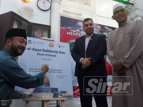 Mukhriz menurunkan tandatangan sebagai tanda solidariti kepada Palestin. Turut kelihatan (dari kanan) Dr Ismail dan Dr Sharif.