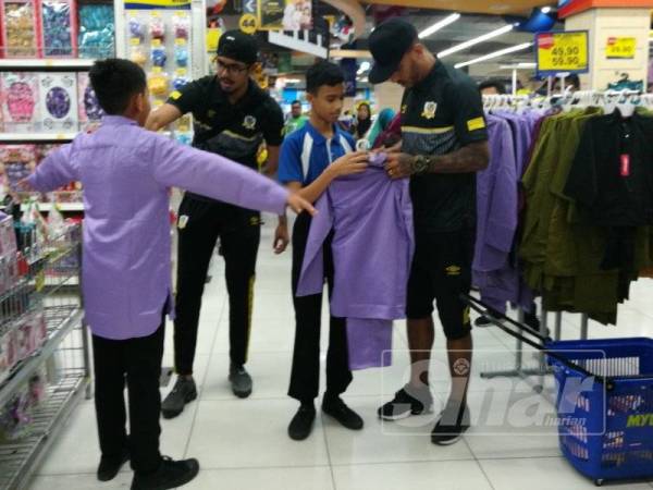 Pemain Perak, Muhammad Hafizul Hakim dan pemain import Leandro Dos Santos membantu mencari baju raya pada program berkenaan.