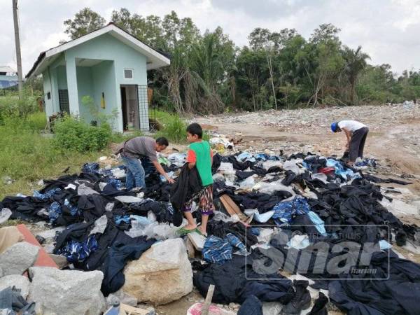 Longgokan baju PLKN yang dibuang atas tanah lapang di Tasik Biru Kundang diambil orang awam.