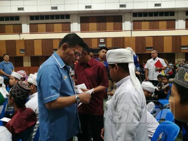 Saifuddin menyampaikan sumbangan kepada seorang pelajar tahfiz dalam program hari ini.