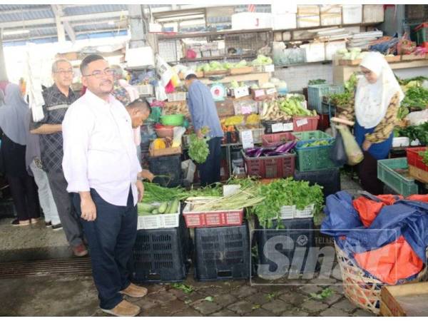 Mujahid (kiri) meninjau permasalahan dihadapi peniaga sayur di Pasar Awam Parit Buntar dalam sesi lawatan hari ini.