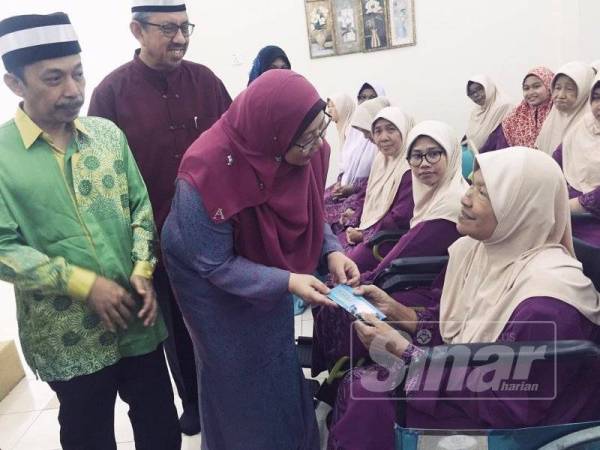 Fuziah (tengah) menyampaikan sumbangan kepada penghuni warga emas Kompleks Asnaf MUIP hari ini.