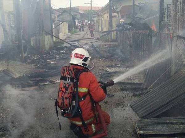 Anggota Bomba dan Penyelamat mengawal kebakaran di dua rumah di Kampung Baru Bidor, di sini hari ini.