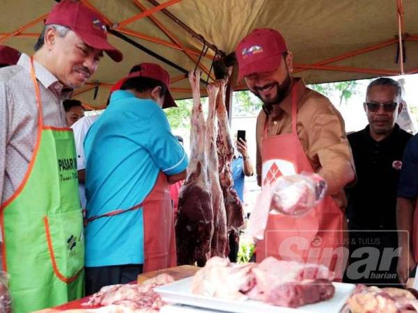 Mukhriz (tengah) tidak melepaskan peluang memotong daging di gerai jualan ketika meninjau suasana di Pasar Tani Taman Wira Mergong.