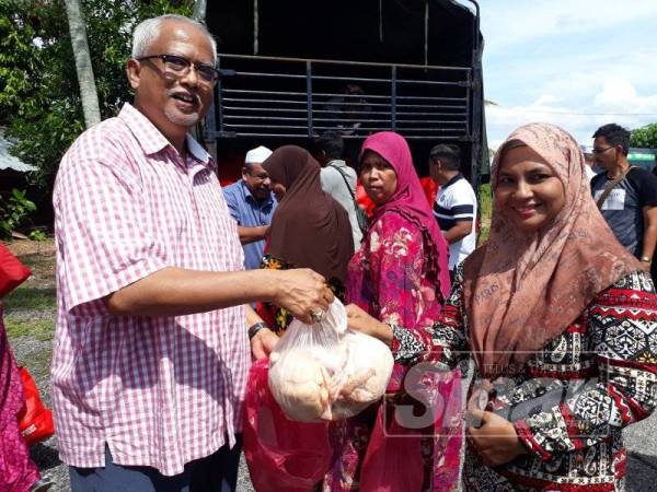 Mahfuz (kiri) mengagihkan sumbangan kepada penerima terpilih di Kampung Alor Senibung di sini, hari ini.