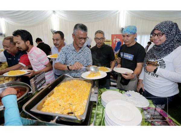 Azman (tiga,kanan) membantu rakan-rakan media mengambil juadah berbuka.