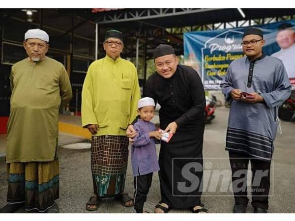 Rizam dua kanan menyampaikan sumbangan kepada salah seorang penerima pada Program Berbuka Puasa dan Sumbangan Anak Yatim dan Asnaf di Masjid Tebuk Mufrad di sini.