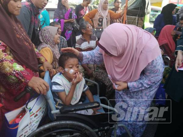 Fuziah beramah mesra bersama kanak-kanak OKU ketika menyampaikan sumbangan duit raya pada Majlis Pelancaran Pasar Tani Khas Pra Syawal Peringkat Negeri Pahang di sini semalam.