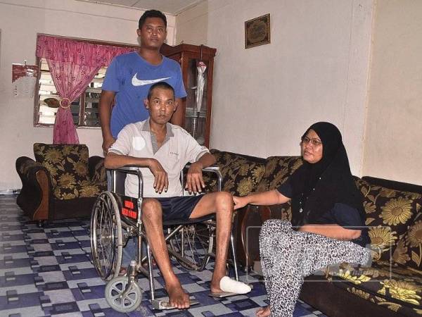 Muhammad Razmi Firdaus (belakang) bersama ibu bapanya yang diserang angin ahnar di rumah mereka di Perumahan Awam Labis, Segamat. 