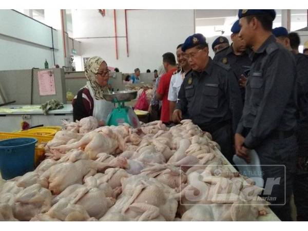 Suhaimi (dua dari kanan) memeriksa harga ayam yang merupakan antara barangan di bawah SHMMP di Pasar Ayam Ipoh di sini hari ini.