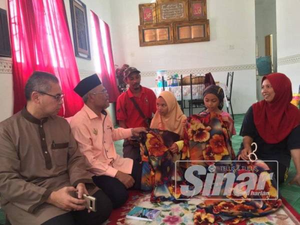 Yahaya ( dua dari kiri) bersama Mohamad Fariz (kiri) melihat baju raya anak-anak Kamsiah (kanan) yang beraya di rumah baharu mereka.
