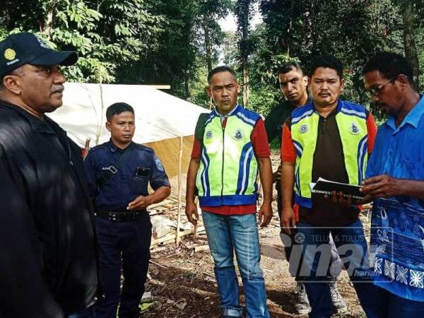 Ketua Polis Gua Musang, Superintendan Mohd Taufik Maidin (kiri) bersama anggotanya turun meninjau kawasan penempatan baharu penduduk orang asli Kuala Koh semalam.