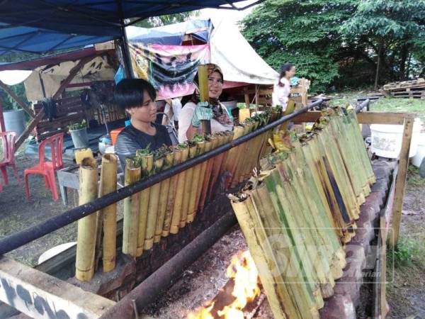 Sanisah menunjukkan lemang yang sedia dijual kepada pelanggan di Gerai Lemang USA di Jalan Pandamaran.