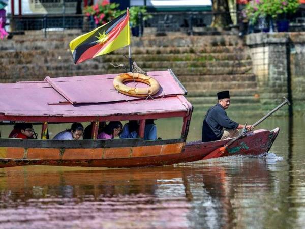 Pengusaha perahu penambang, Sapuan Abun, 61, (depan) bersama penumpangnya menuju ke Pangkalan Sapi berhampiran Tebingan Sungai Kuching pada hari kedua Aidilfitri. - FOTO BERNAMA