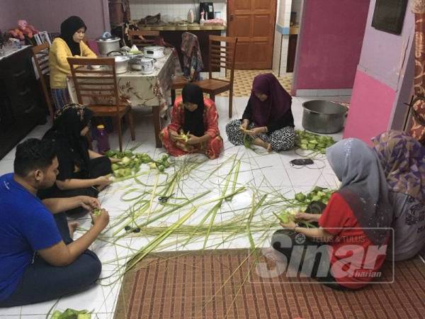 Aziyan (duduk bawah tiga dari kiri) bersama ahli keluarga menyiapkan kelongsong ketupat sebagai persediaan Aidilfitri.