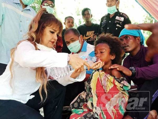 Sabrina memberi minum kepada anak-anak Orang Asli yang demam berada di bawah khemah penempatan baharu di sini.