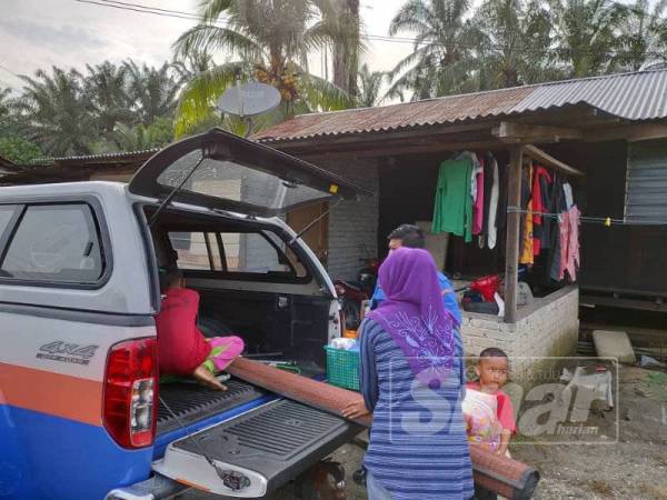 Anggota Angkatan Pertahanan Awam (APM) membantu mangsa banjir dari PPS SK Changkat Jong pulang ke rumah mereka pagi ini.