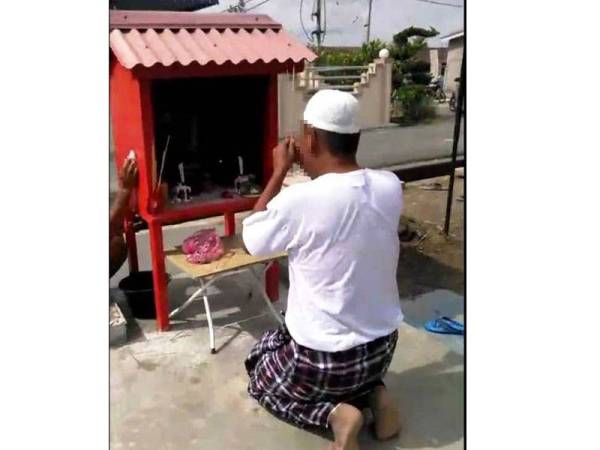 Rakaman gambar dari klip video tular dalam Facebook menunjukkan aksi suspek berpakaian kain pelekat dan kopiah menjalani aktiviti pemujaan tokong Dato Kong di Taman Piandang Indah, Tanjung Piandang baru-baru ini.