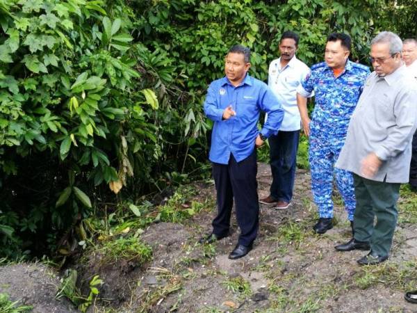 Khairul Anwar (kiri) melihat aliran air yang tesumbat di kampung berkenaan.